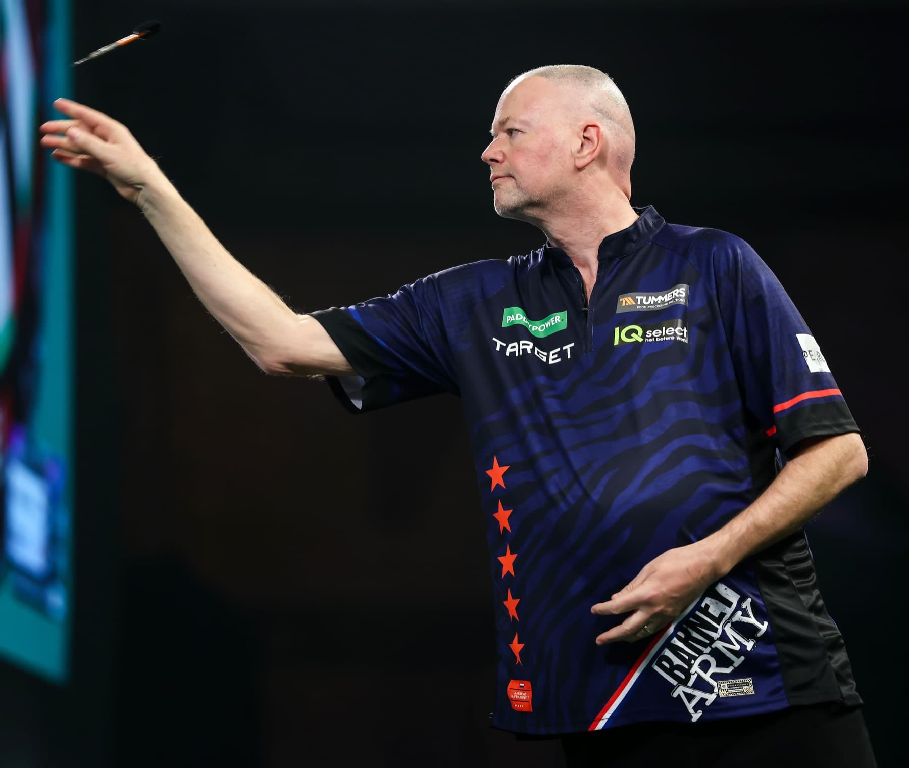 Raymond Van Barneveld mid-throw on stage with the dart in the air