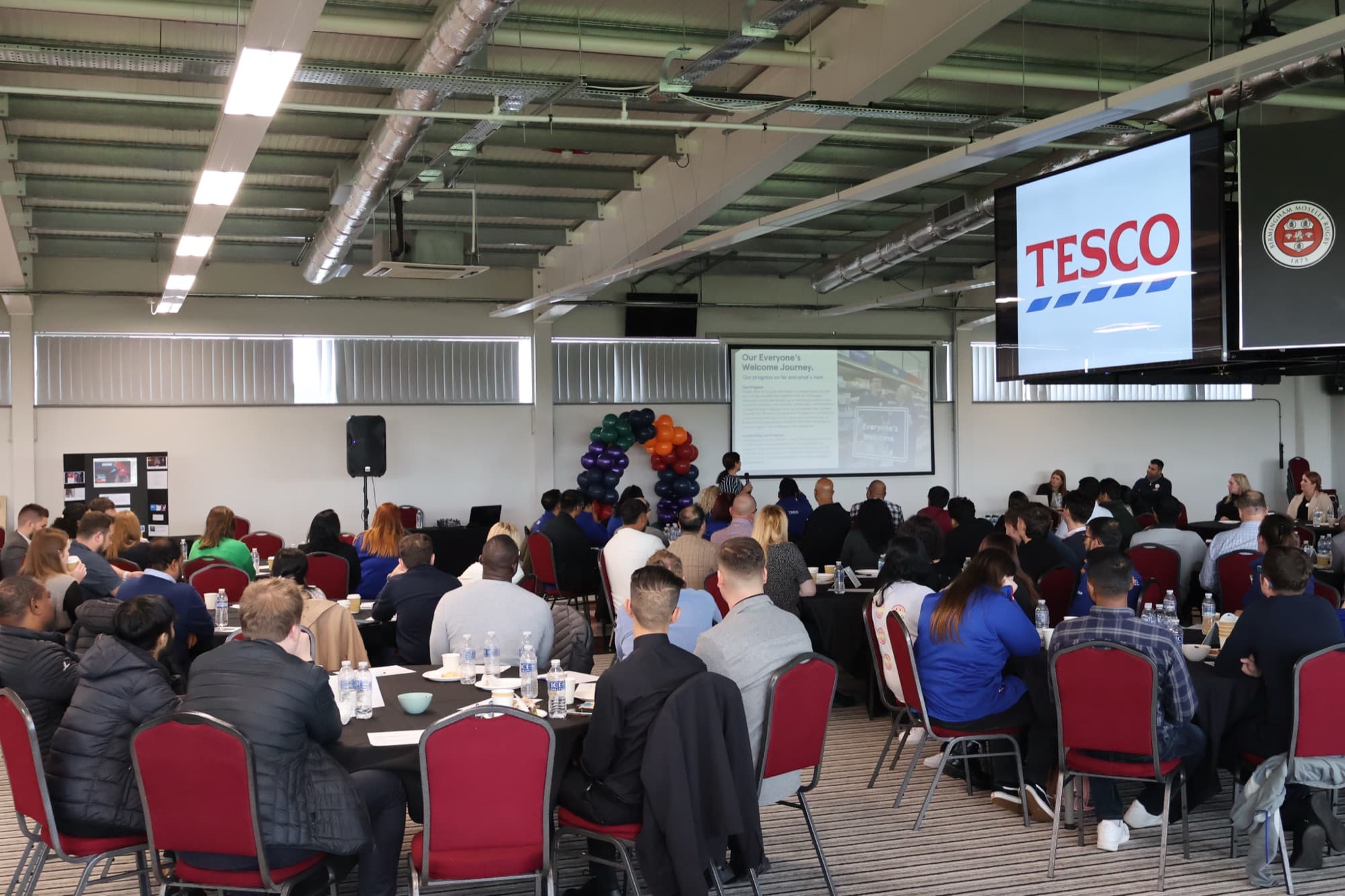 A corporate conference in The Reddings Suite, cabaret seating with a presentation screen