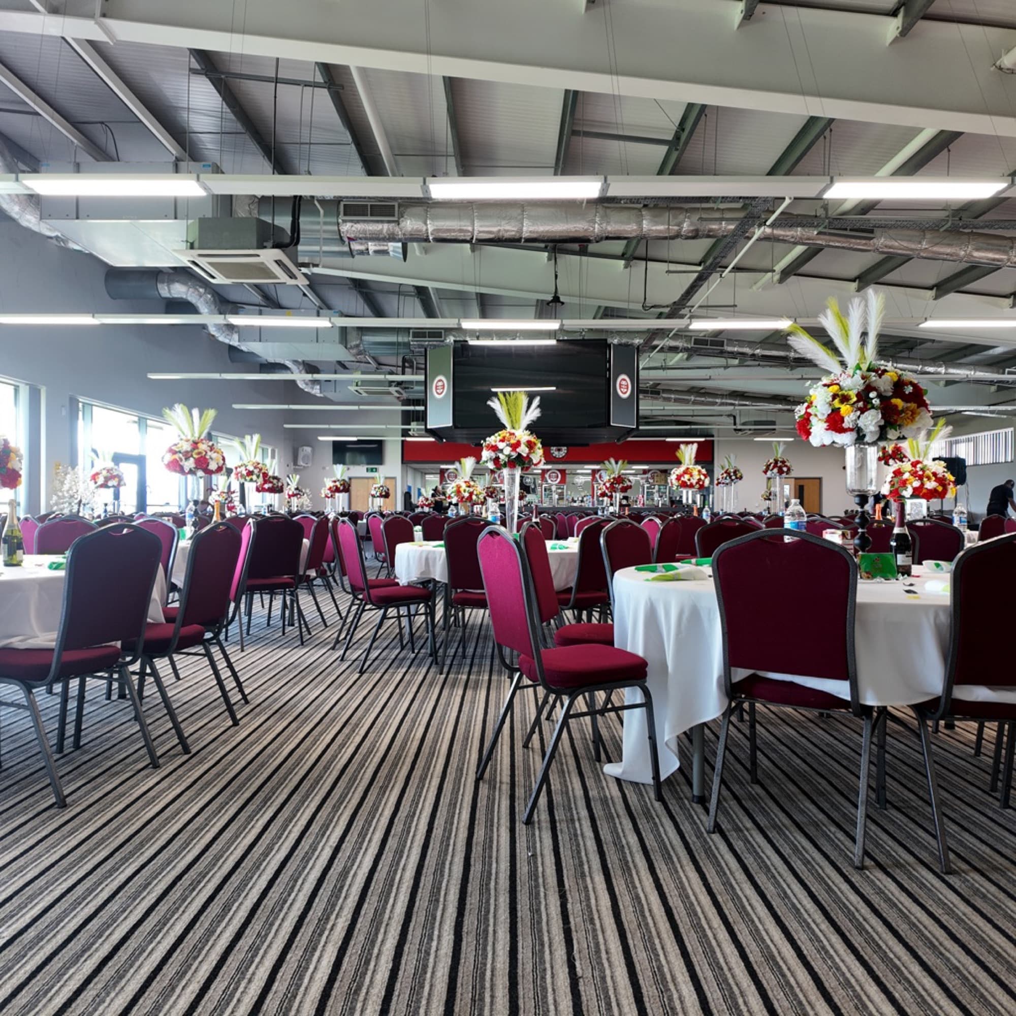 The Reddings Suite laid out with round tables and floral centrepieces for a gathering